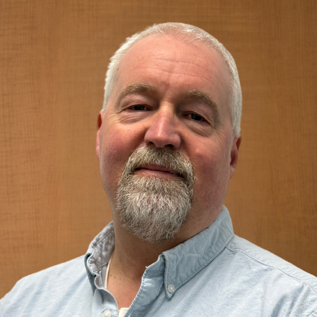 A profile photo of a Nick Anderson wearing a blue shirt against a brown background. 